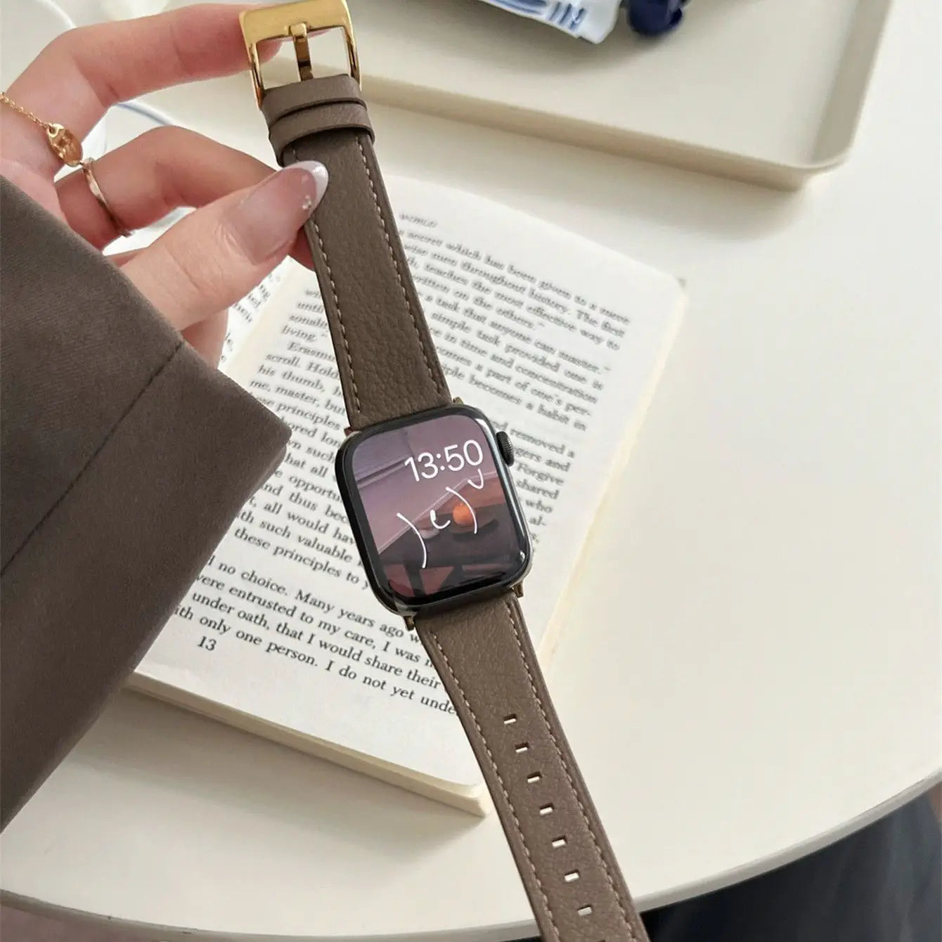Smartwatch with a brown strap held by a hand on a book