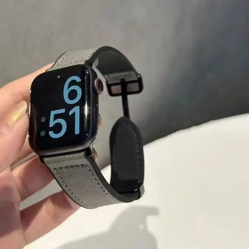 Smartwatch with a gray band held by a hand against a neutral background