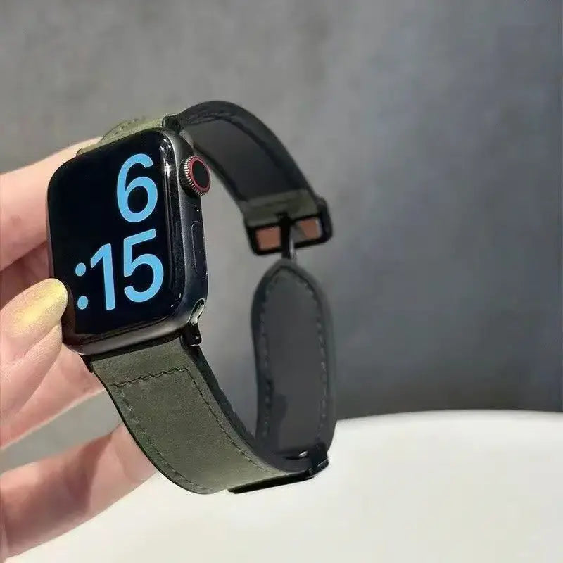 Smartwatch with a green leather strap held by a hand against a gray background
