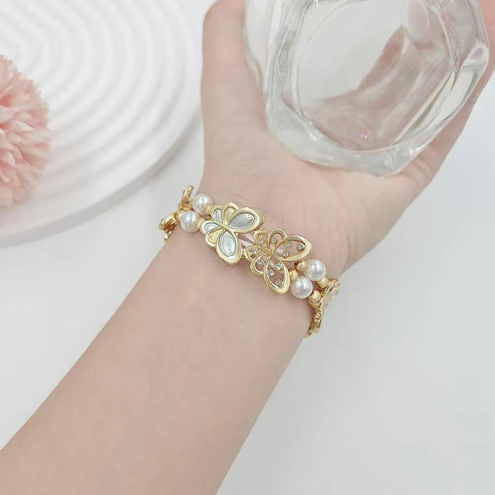Gold bracelet with pearls on a wrist against a white background