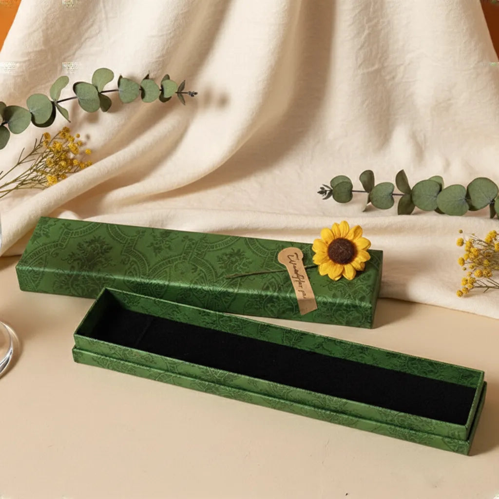 Green jewelry box with a sunflower decoration on a beige fabric background