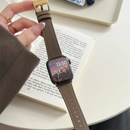 Smartwatch with a brown strap held by a hand on a book