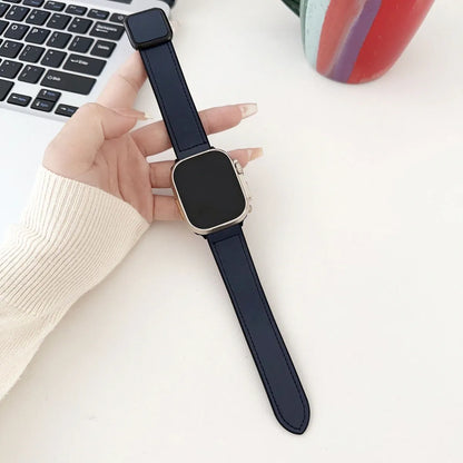 Smartwatch with a dark blue strap held by a hand on a light surface.