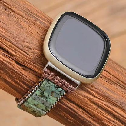 Smartwatch with a brown and green woven strap on a wooden surface