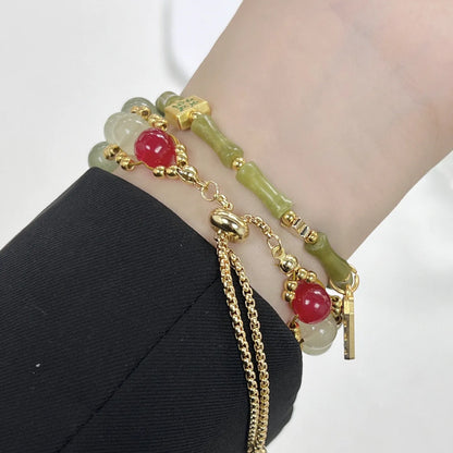Bracelet with green beads and gold chain on a wrist against a white background