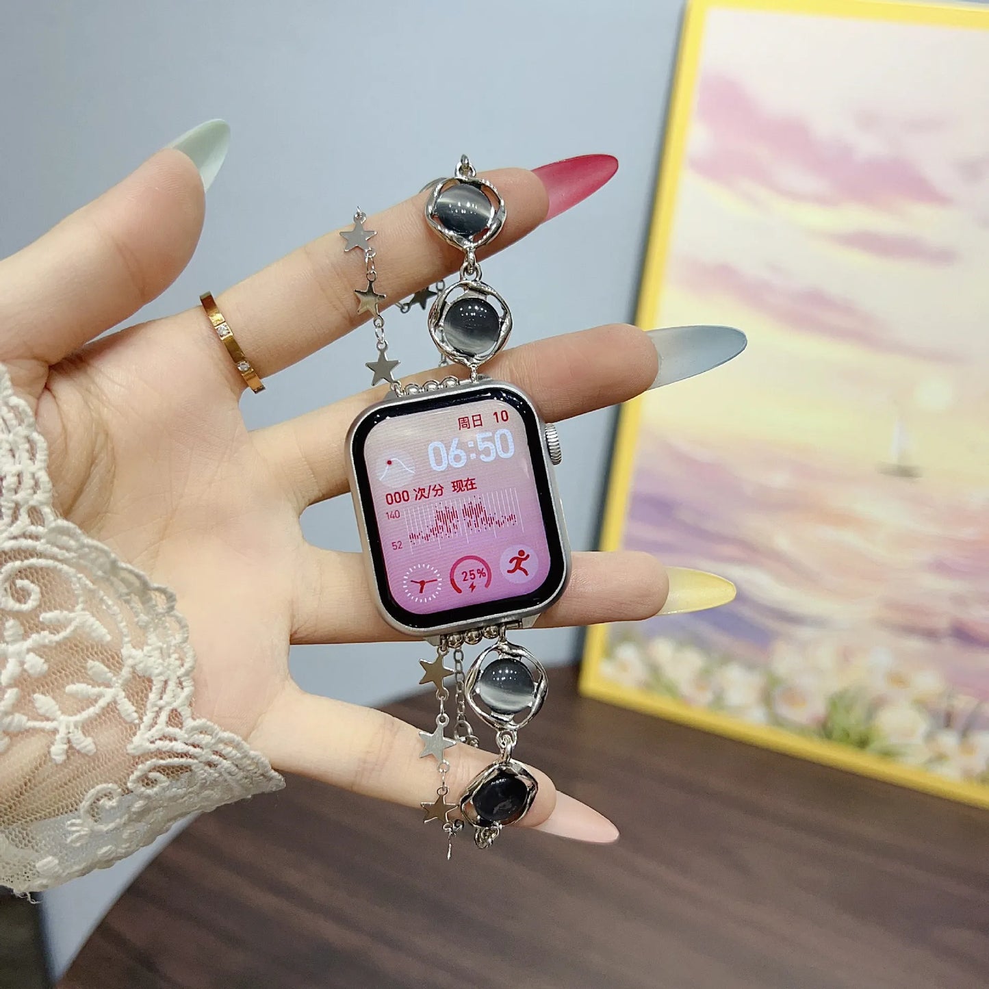 Smartwatch charm with decorative elements held by a hand against a blurred background