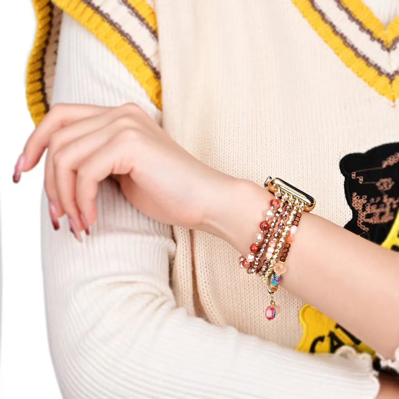 Close-up of a hand wearing a colorful bracelet on a person wearing a patterned sweater.