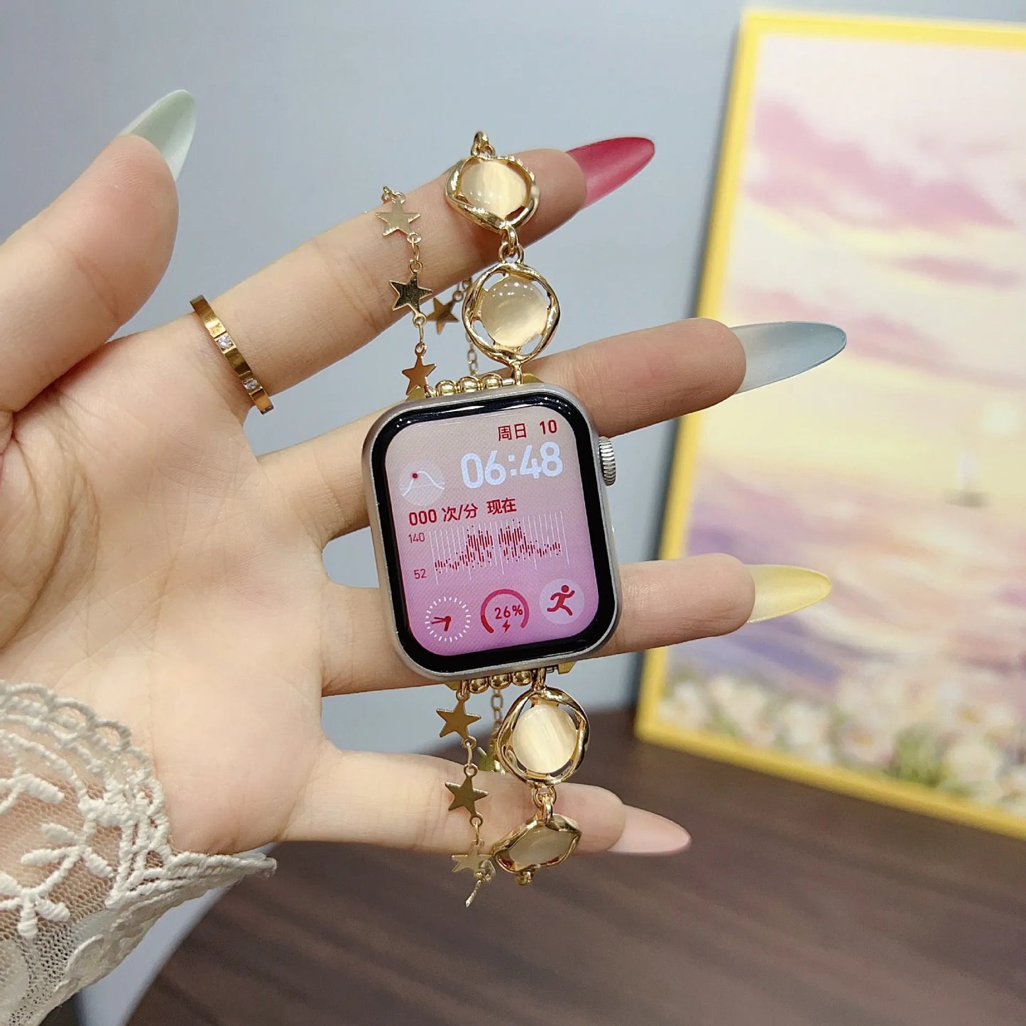 Smartwatch with decorative charm held by a hand against a blurred background