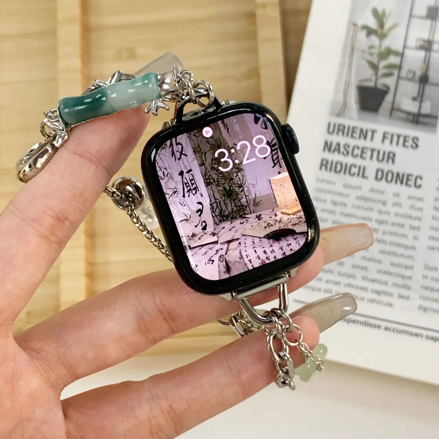 Smartwatch case with charm held by a hand, with a blurred background