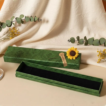 Green jewelry box with a sunflower decoration on a beige fabric background
